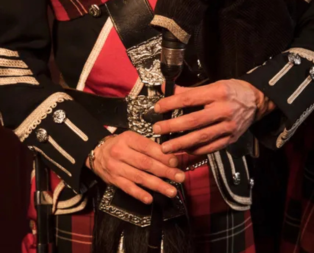A man in a kilt plays the bagpipes.