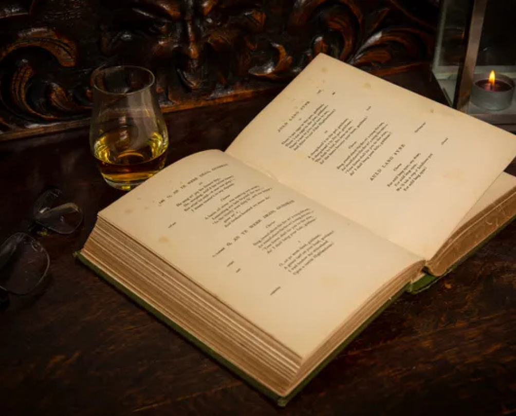 An old book with yellowed pages open on an old desk.