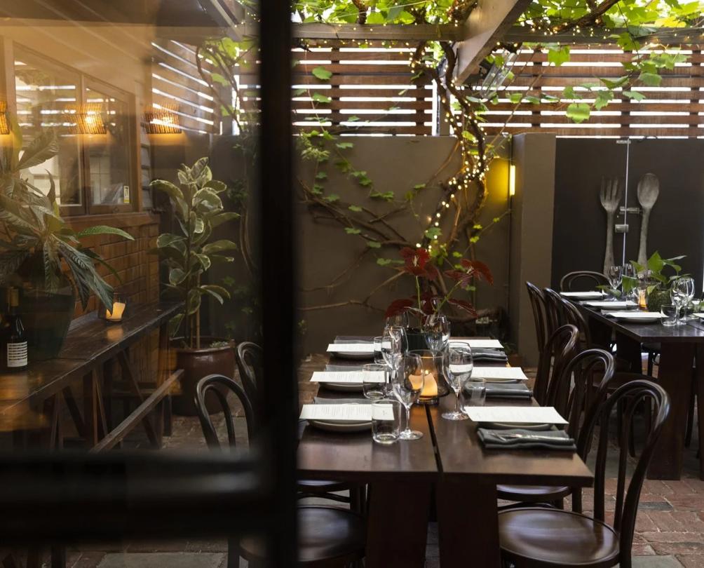 A small, leafy courtyard with two long tables dressed for lunch.