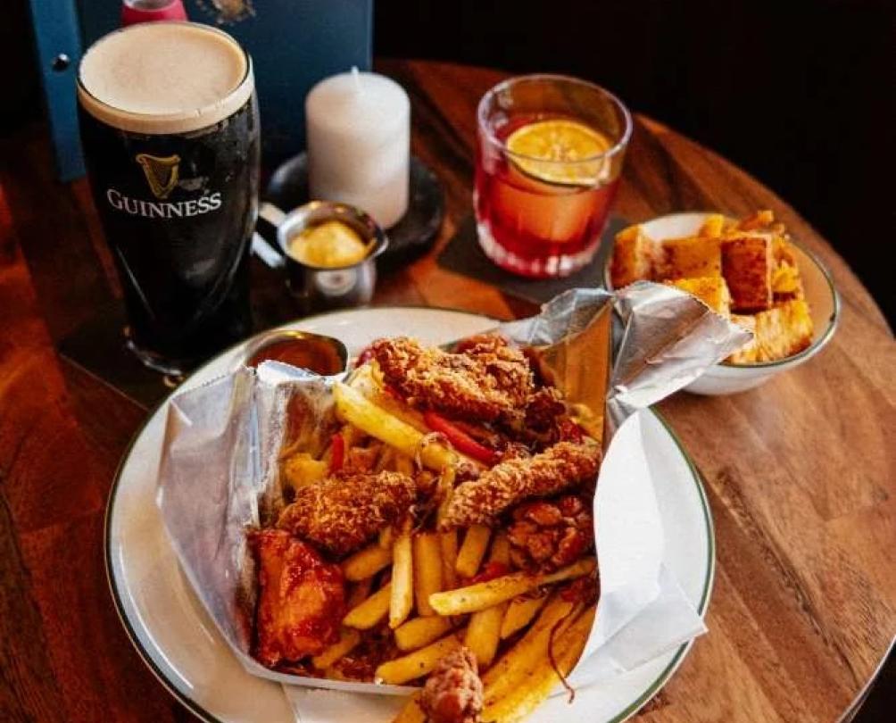 A small table with a pint of Guinness and a spice bag on it.