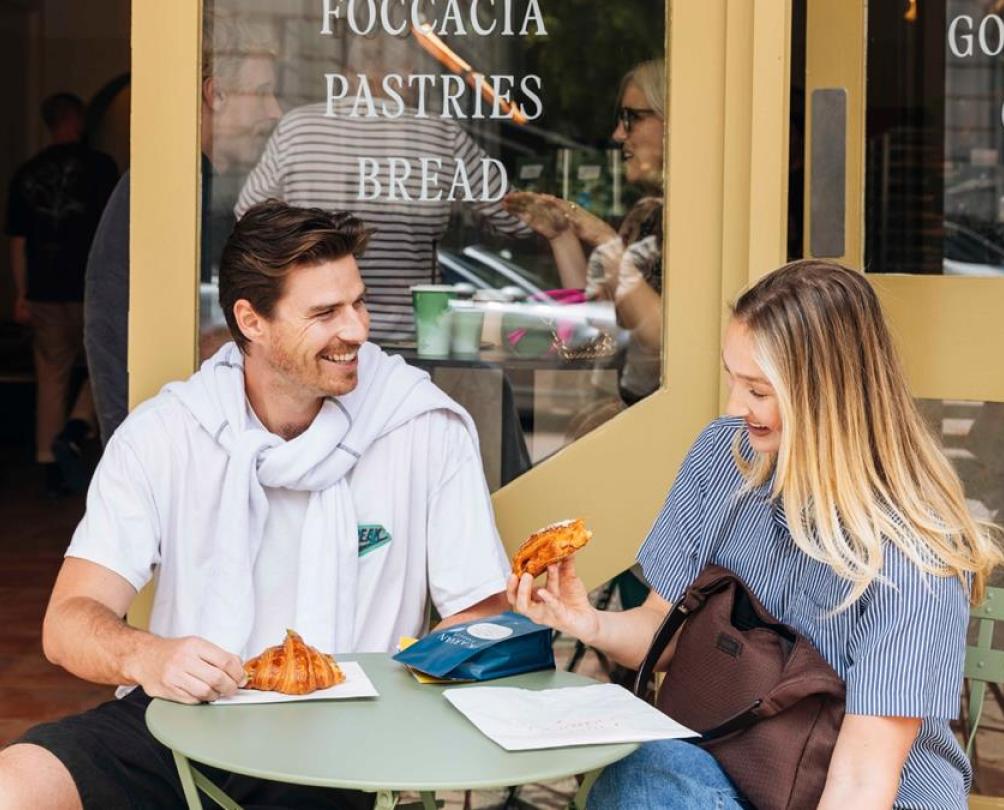 A young couple enjoying a pastry outside an Italian cafe.