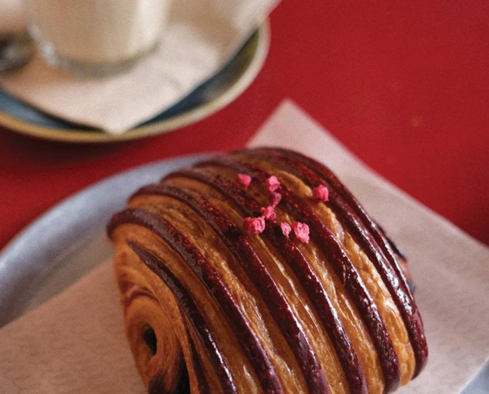 A sweet pastry and a coffee on blue plates on a red table.