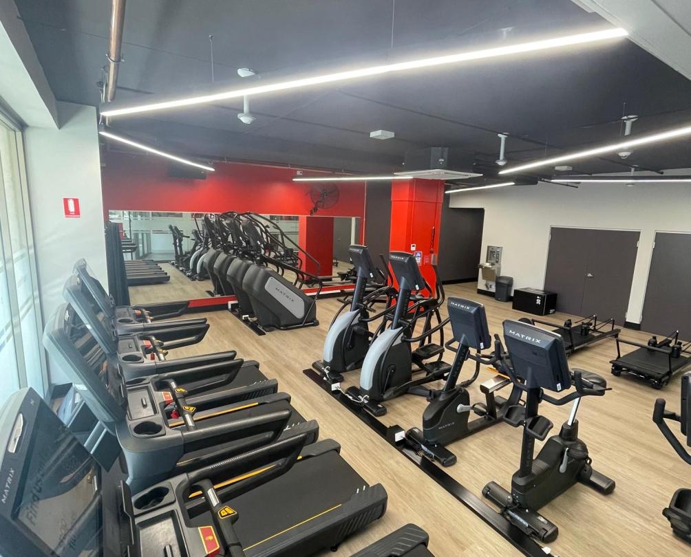 images of treadmills and stationary bikes in a line inside a gym. 
