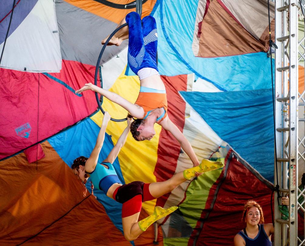 kids in colourful clothing hanging from circus rigging upside down