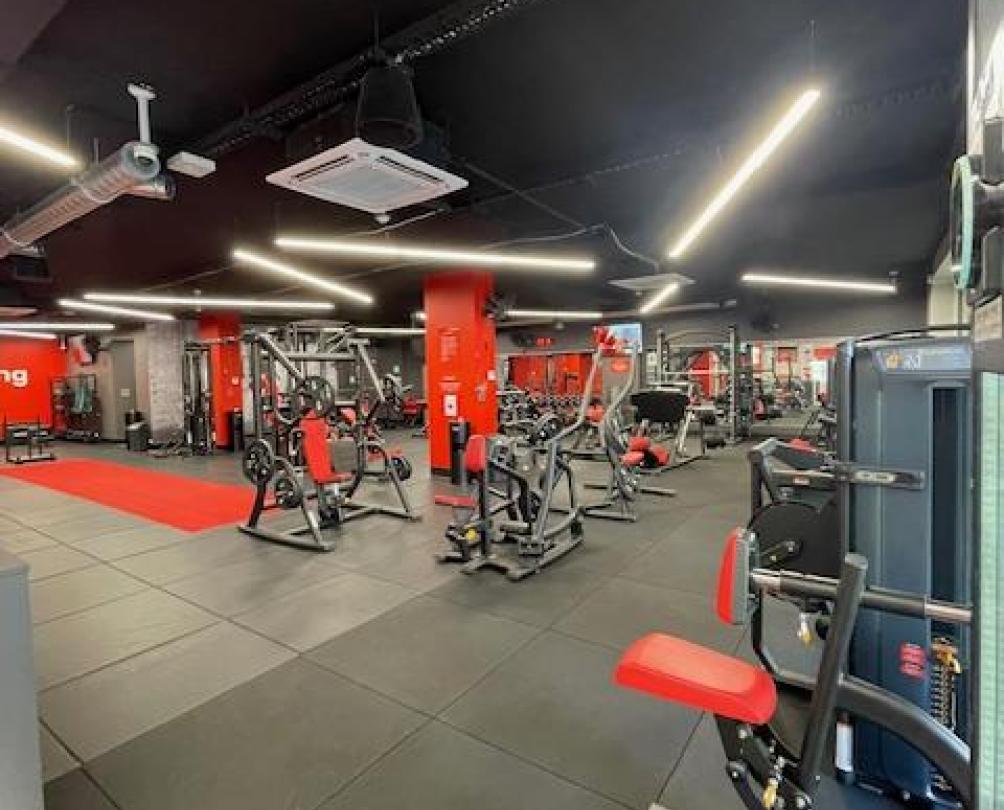view looking into the front of the gym with red mats and walls and black gym equipment 