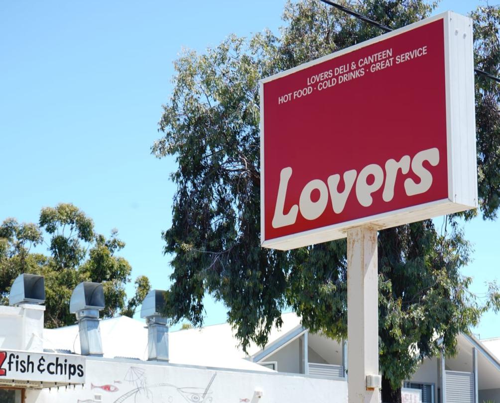 Red lovers sign with green trees behind