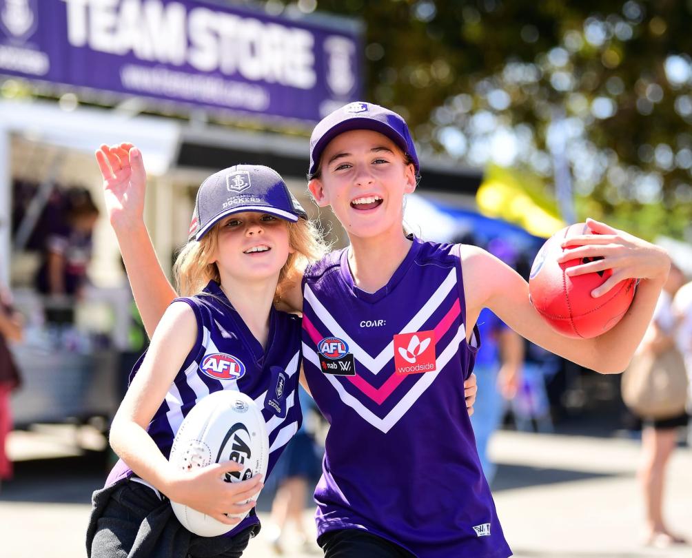two kids in purple at the Fremantle Oval with balls in their hands