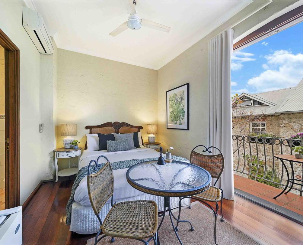 a suite with a bed, a table and chairs and a little balcony in Fremantle 