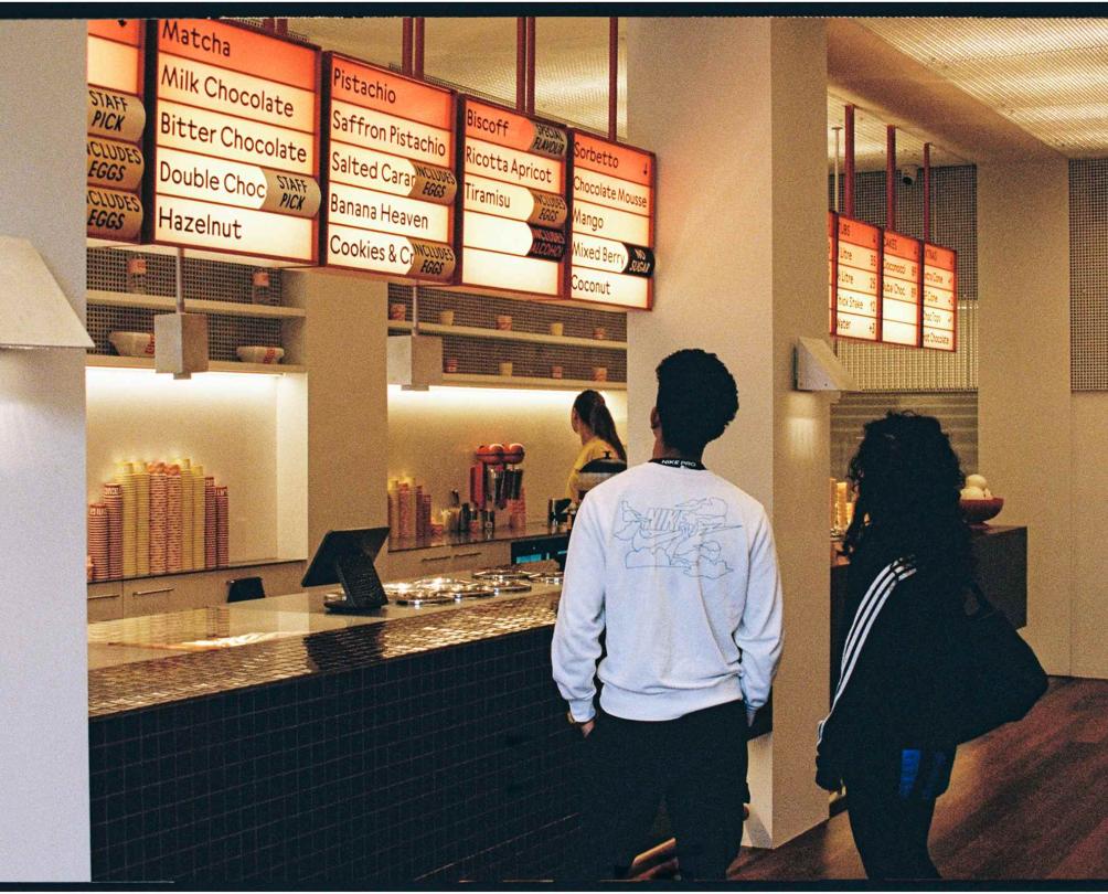 two people facing an ice cream counter looking up at the flavours 
