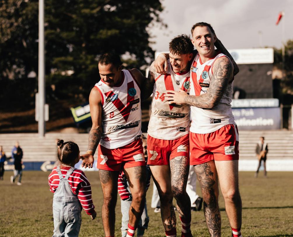 a group of football players on a pitch looking at a kid 