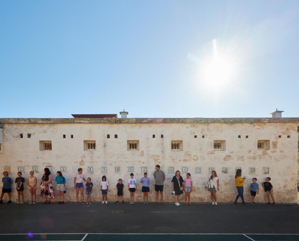 families standing against a wall at the Fremantle Prison during school holidays 