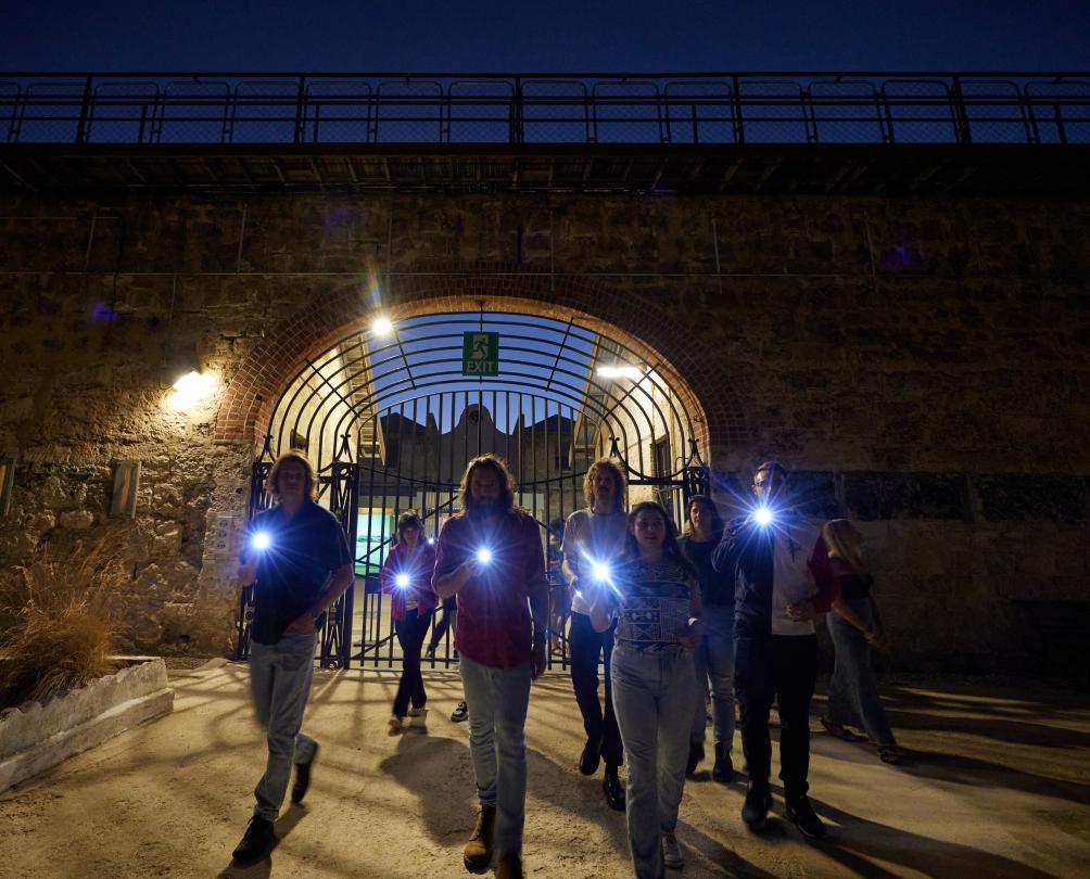 a group of people with flashlights on the torchlight tour at Fremantle Prison