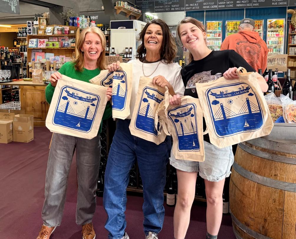 people in old bridge cellars holding up free tote bags 