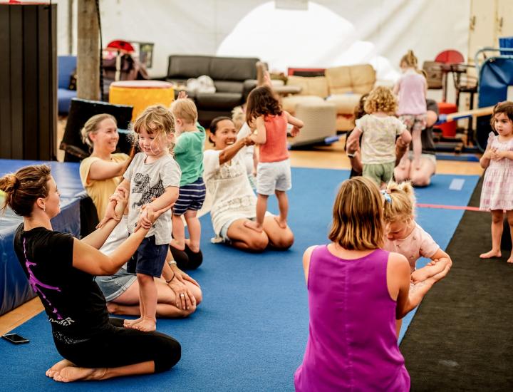 parents assisting toddlers to do circus tricks