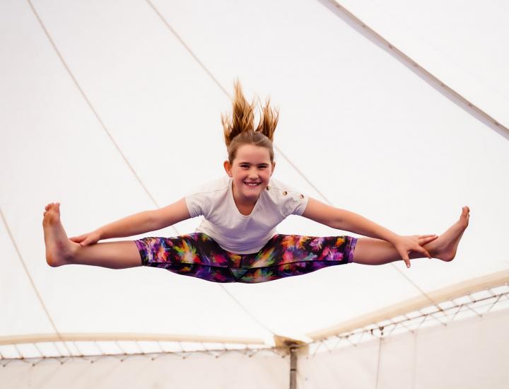 girl in the air doing the splits in the big top