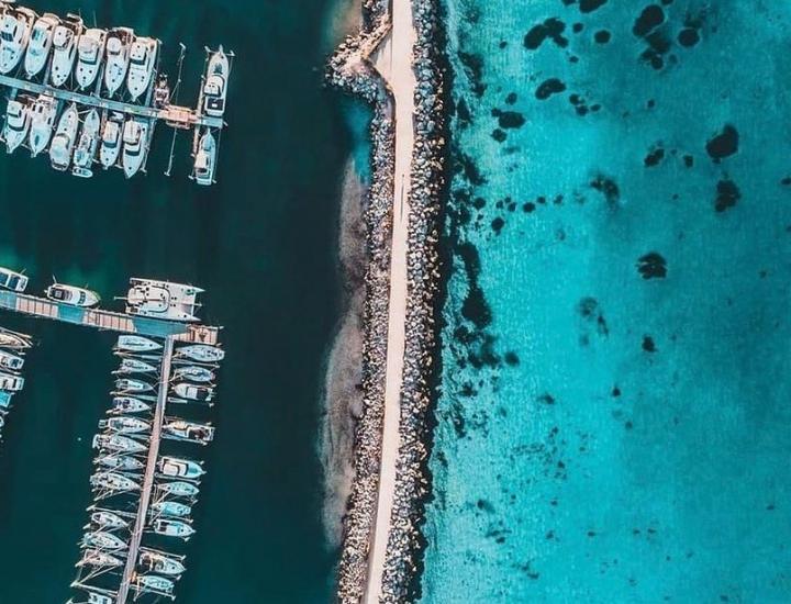 Aerial photo of Fremantle sailing club. to the left there are boats parked in rows along the jetty to the left there is a breathtaking turquoise ocean. 