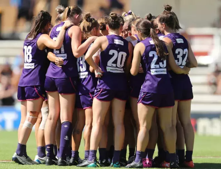 AFLW Dockers team - players in purple uniforms huddled together