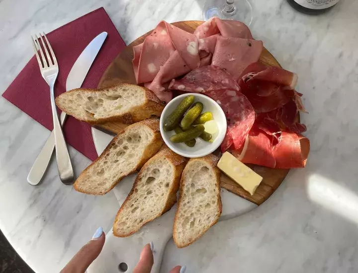 table set with wine, bread and sliced meats