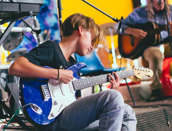 young boy playing guitar at penny lane music school