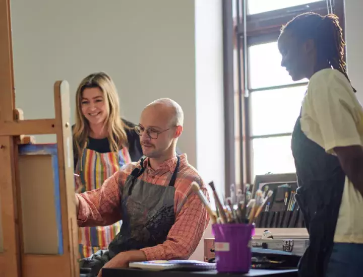 person paints at an easel in a light-filled, heritage room