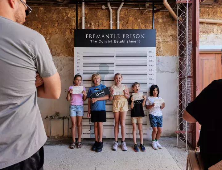 Kids standing in front of photo wall at Fremantle Prison on a school holiday tour - captured by Jess Wyld