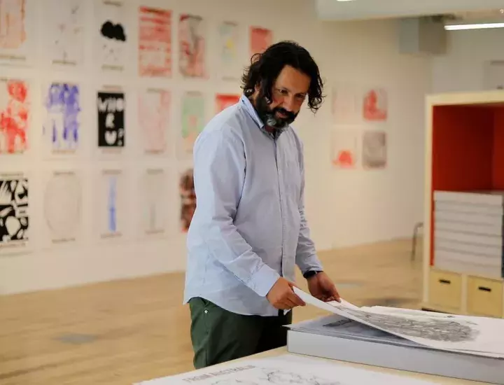 A man in an art gallery studio studies print works.