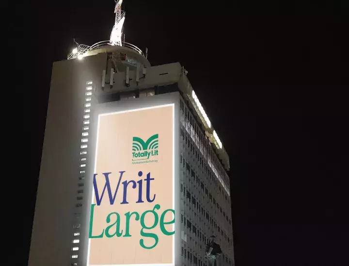  A tall building with a large projection on it with the words 'Writ Large'.