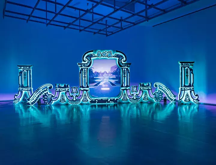 A blue room with a bright turquoise blue mirror installation depicting a portal to a blue and purple world.