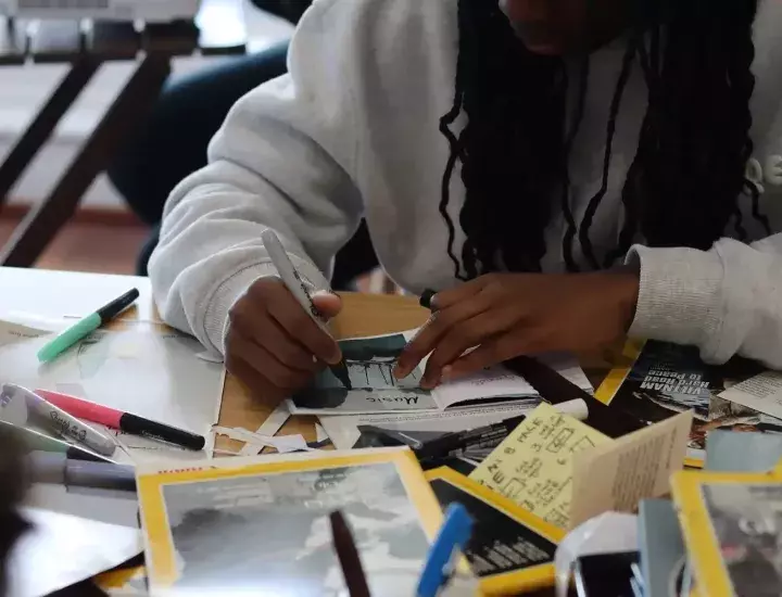 A young person at a table filled with various art and scrapbooking materials.