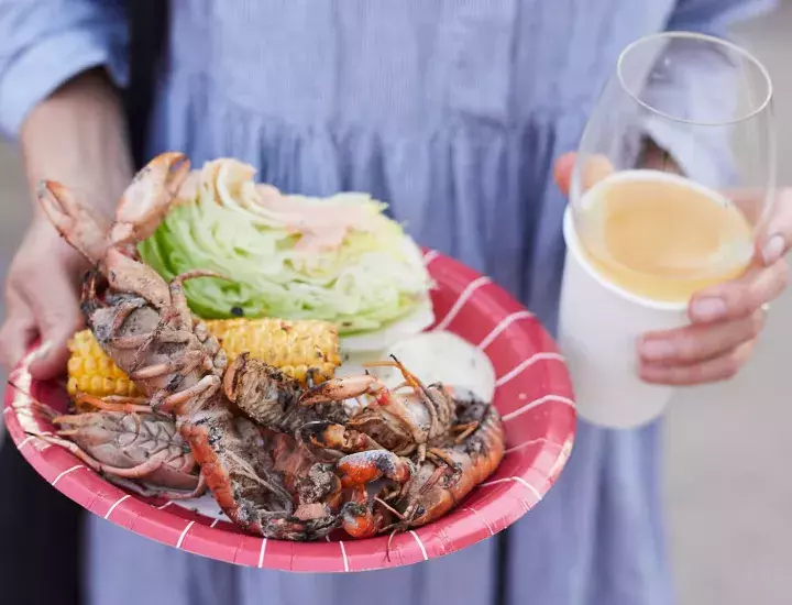 Woman holding a plate of food and glass of drink