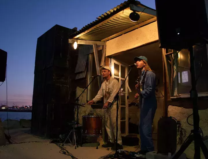 Two musicians playing keyboard and guitar outside a hut at Bathers beach
