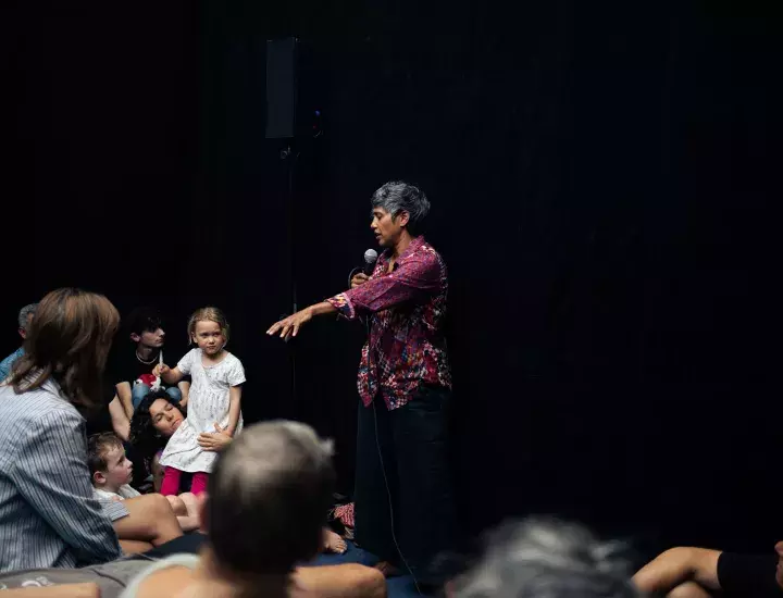 Woman speaking into a microphone in a room full of people