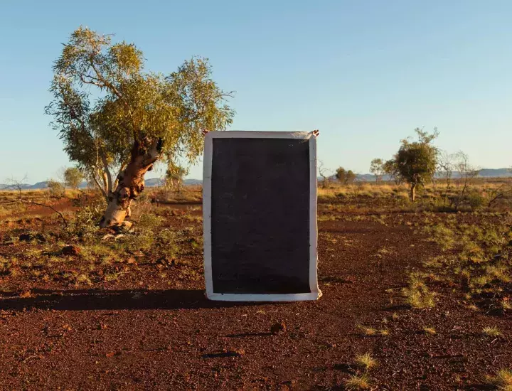 A black canvas with a white border stands alone in an Australian desert landscape.