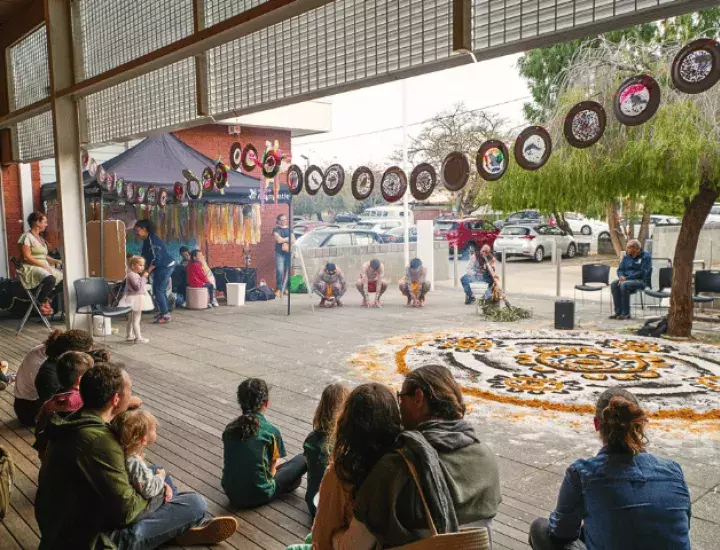 a cultural celebration with Aboriginal dancers and a didgeridoo with a design on the ground and children and families watching